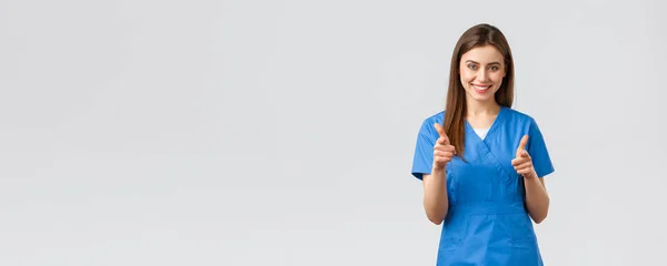 Trabajadores de la salud, prevenir virus, seguros y concepto de medicina. Enfermera sonriente entusiasta, doctora en uniformes azules, apuntándose con pistolas, eligiendo, invitando a los clientes a la clínica — Foto de Stock