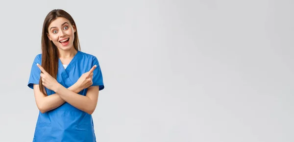 Медицинские работники, предотвратить вирус, страхование и медицина концепции. Энтузиастская улыбающаяся медсестра, доктор в синем халате, указывающая пальцами влево направо, показывающая два продукта или баннера — стоковое фото