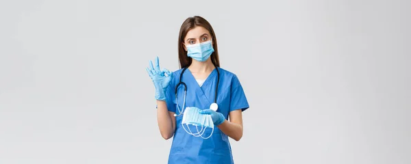 Covid-19, prévention du virus, santé, concept des travailleurs de la santé. Infirmière professionnelle ou médecin en blouse bleue et équipement de protection individuelle, montrer le signe correct et donner le masque médical — Photo
