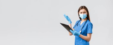 Covid-19, virüsün önlenmesi, sağlık, sağlık çalışanları ve karantina konsepti. Mavi önlüklü ve tıbbi maskeli kadın hemşire ya da doktor, panoda saçma sapan şeyler okuyor.