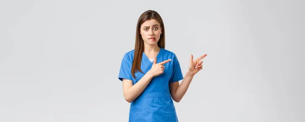 Sağlık çalışanları, virüsü, sigortayı ve ilaç konseptini engelleyin. Gergin kadın stajyer hastanede dikilmekten endişeleniyor. Doktor ya da hemşire gergin bir şekilde dudağını ısırıyor ve parmaklarını sağa çeviriyor. — Stok fotoğraf