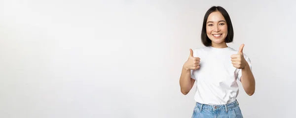 快乐美丽的韩国姑娘，高高兴兴地举起大拇指，高兴地微笑着，像鼻涕一样，推荐着，站在白色的背景上 — 图库照片