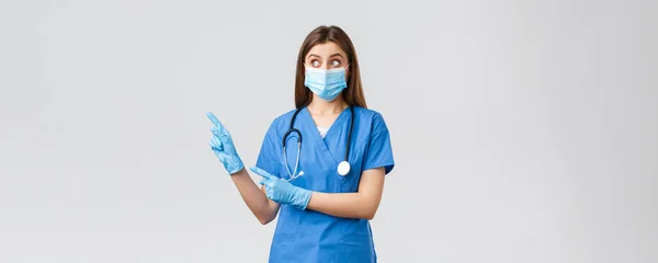 Covid-19, megelőzés vírus, egészségügyi dolgozók és karantén koncepció. Meglepett női nővér vagy orvos kék köpenyben, orvosi maszk és kesztyű, keres és mutat balra kíváncsi — Stock Fotó