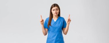 Sağlık çalışanları, virüsü, sigortayı ve ilaç konseptini engelleyin. Endişeli ya da gergin hemşire ya da doktor mavi önlüklü, ısıran dudaklı endişeli, yukarı bakan, baştan çıkarıcı, gri arka planlı