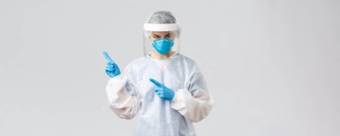 Covid-19, virüsün önlenmesi, sağlık, sağlık çalışanları ve karantina konsepti. Profesyonel doktor ya da hemşire Ncov, Coronavirus 'la savaşıyor, koruyucu giysi ve solunum cihazı takıyor, sol elini işaret ediyor.