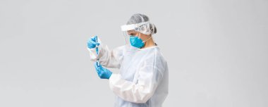 Covid-19, tıbbi araştırma, teşhis, sağlık çalışanları ve karantina konsepti. Korunma ekipmanlarında doktor, Coronavirus aşısı tutuyor ve şırıngaya koyuyor, iğneyi hasta yapıyor.