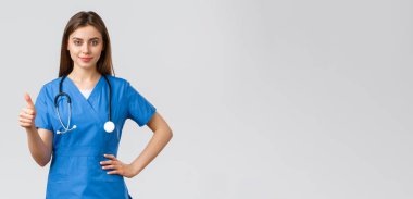 Tıp çalışanları, covid-19 ve aşı konsepti. Kendine güvenen profesyonel doktor, mavi önlüklü ve steteskoplu bayan hemşire, baş parmaklarınızı kaldırın, klinikteki en iyi hizmeti sağlayın veya garanti edin.