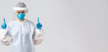 Covid-19, virüsün önlenmesi, sağlık, sağlık çalışanları ve karantina konsepti. Hasta Coronavirüs hastalarıyla çalışan kararlı genç bir doktor ya da hemşire. Parmakla işaret ediyor, koruyucu elbise giyiyor.