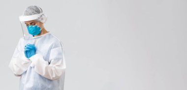 Covid-19, virüsün önlenmesi, sağlık, sağlık çalışanları ve karantina konsepti. Umut verici doktor ya da hemşire kişisel koruyucu giysi, yüz kalkanı ve tıbbi maske, hastaların koronavirüsü iyileştirmesi için dua ediyor.