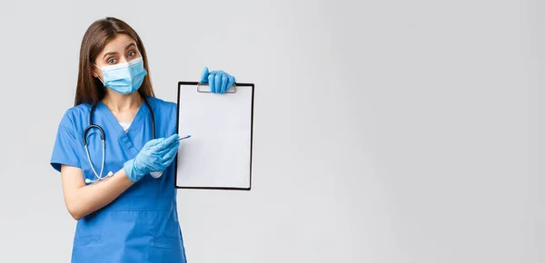 Covid-19，防止病毒、健康、保健工作者和检疫概念。穿着蓝色刷子和医疗面罩的友善的女护士或女医生，请在剪贴板上解释相关信息，并指出相关文件 — 图库照片