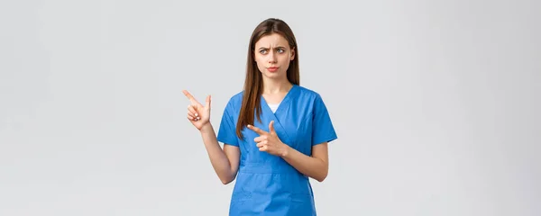 의료 종사자들, 바이러스 예방, 보험, 그리고 의학 개념. 뭔가 잘못 됐어. 심각하게 불쾌 한 파란 수술복을 입은 간호사나 의사, 눈살을 찌푸리고 왼쪽을 가리켜서 걱정 — 스톡 사진