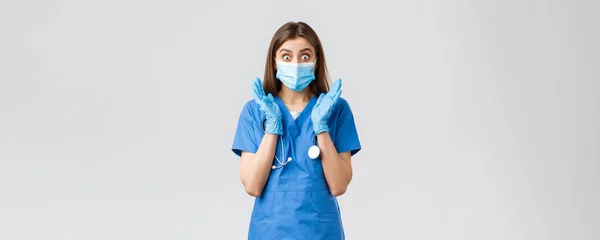 Covid-19, zapobieganie wirusom, zdrowiu, pracownikom służby zdrowia i koncepcji kwarantanny. Zaskoczony i zszokowany pielęgniarka kobieta w niebieskim fartuchu i maski medycznej, dysząc wygląd zdumiewający aparat — Zdjęcie stockowe