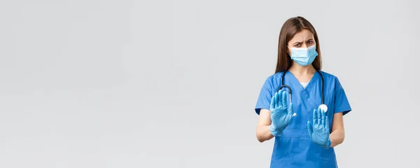 Covid-19, het voorkomen van virus, gezondheid, gezondheidszorg werknemers concept. Nee, bedankt. Ontevreden en terughoudend vrouwelijke verpleegkundige of arts in medisch masker en scrubs, stop, afwijzing of weigering teken — Stockfoto