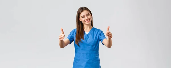 Healthcare workers, prevent virus, insurance and medicine concept. Supportive cheerful female nurse or doctor in scrubs, thumbs-up recommend clinic, advice click link or visit pharmacy — Stock Photo, Image