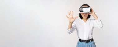 Vr sohbet. Asyalı kız sanal gerçeklik gözlükleriyle merhaba diyor, coşkuyla gülümsüyor, iletişim konsepti ve gelecek teknolojisi, beyaz arka plan