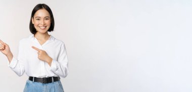 Gülümseyen genç ofis hanımı, Asyalı girişimci sol elini göstererek müşteri bilgilerini, fotokopi alanındaki pankart çizelgesini, beyaz arkaplanı gösteriyor