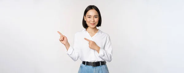 Gülümseyen genç ofis hanımı, Asyalı girişimci sol elini göstererek müşteri bilgilerini, fotokopi alanındaki pankart çizelgesini, beyaz arkaplanı gösteriyor — Stok fotoğraf