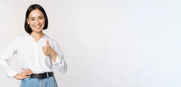 Imagen de mujer asiática confiada mostrando el pulgar hacia arriba en aprobación, recomendando, como smth bueno, de pie sobre fondo blanco — Foto de Stock