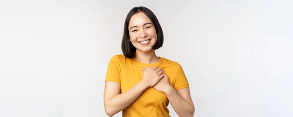 浪漫的亚洲女朋友，手牵着心，心地善良地微笑着，穿着黄T恤站在白色的背景上 — 图库照片