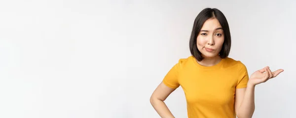 Na und. Unbelästigte asiatische Frau zuckt mit den Schultern, sieht ahnungslos aus, steht vor weißem Hintergrund — Stockfoto