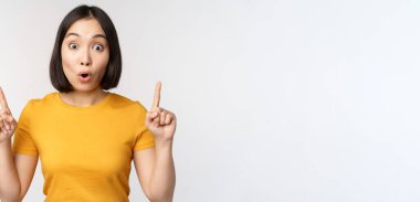 Etkilenmiş Asyalı bir kızın portresi, parmaklarını havaya kaldırarak, 
