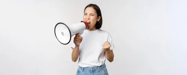 stock image Confident asian woman shouting in megaphone, screaming and protesting. Girl activist using speaker to speak louder, standing over white background