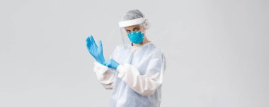 Covid-19, virüsün önlenmesi, sağlık, sağlık çalışanları ve karantina konsepti. Kararlı genç kadın doktor, PPE koruyucu ekipman hemşiresi, maske takan lastik eldivenler, aşı üzerinde çalışan
