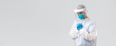 Covid-19, virüsün önlenmesi, sağlık, sağlık çalışanları ve karantina konsepti. Umut verici doktor ya da hemşire kişisel koruyucu giysi, yüz kalkanı ve tıbbi maske, hastaların koronavirüsü iyileştirmesi için dua ediyor.