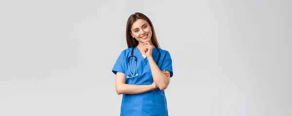 Trabajadores médicos, atención médica, covid-19 y concepto de vacunación. Enfermera bonita sonriente optimista, médico en uniformes azules, clínica de trabajo, mirando con la mirada entusiasta cámara, escuchando a su compañero de trabajo — Foto de Stock