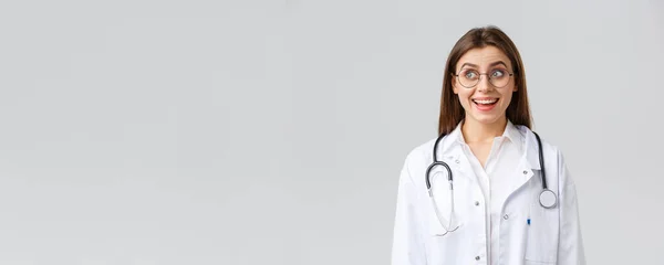 Lucrătorii din domeniul sănătății, medicina, asigurarea și conceptul de pandemie covid-19. Fericit optimist medic de sex feminin, medic cu stetoscop în scrubs alb și ochelari, uita-te la colțul din stânga sus cu zâmbet optimist — Fotografie, imagine de stoc