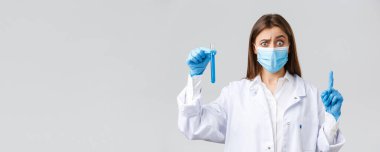 Covid-19, virüsü önleme, sağlık çalışanları ve karantina konsepti. Kişisel koruyucu ekipman, tıbbi maske ve eldiven giyen, Coronavirus aşısı örneği gösteren, emin değilim.