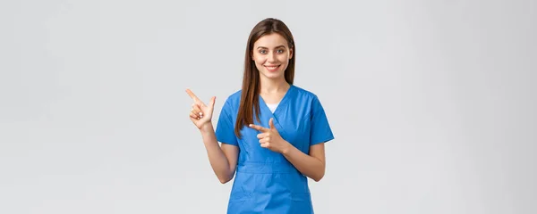 Travailleurs de la santé, prévenir le virus, concept d'assurance et de médecine. Professionnel souriant, attrayant infirmière ou médecin dans les blouses bleues, médecin pointant doigt gauche à la bannière, recommander clinique — Photo