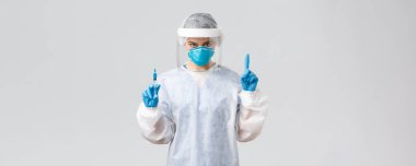 Covid-19, tıbbi araştırma, teşhis, sağlık çalışanları ve karantina konsepti. PPE kostümlü kararlı doktor, kişisel koruyucu ekipman, hasta için koronavirüs aşısı olan şırınga