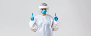 Covid-19, virüsün önlenmesi, sağlık, sağlık çalışanları ve karantina konsepti. Hasta Coronavirüs hastalarıyla çalışan kararlı genç bir doktor ya da hemşire. Parmakla işaret ediyor, koruyucu elbise giyiyor.