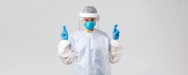 Covid-19, virüsü önleme, sağlık çalışanları konsepti. Doktor ya da hemşire kişisel koruyucu ekipman, solunum cihazı ve yüz kalkanı olan tıbbi giysi, umut dövüşü koronavirüs, şans dileyin.