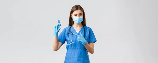 Covid-19, zapobieganie wirusom, zdrowiu, pracownikom służby zdrowia i koncepcji kwarantanny. Ładna pielęgniarka lub lekarz w niebieskim fartuchu, maska medyczna, strzykawka wskazująca ŚOI wypełniona szczepionką przeciw koronawirusowi — Zdjęcie stockowe