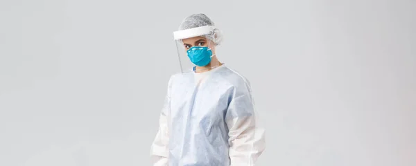 Covid-19, megelőzés vírus, egészségügyi dolgozók és karantén koncepció. Komoly, eltökélt orvos, védőöltönyös női ápolónő PPE, arcmaszk és pajzs, fényképezőgép, betegmentés — Stock Fotó