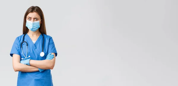 Covid-19，防止病毒、健康、保健工作者和检疫概念。身穿蓝色刷子、听诊器和个人防护装备的疑心重重、忧心忡忡的女护士看上去很可疑 — 图库照片