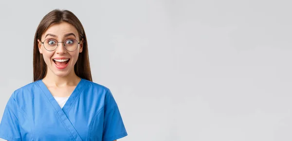 Sağlık çalışanları, ilaç, sigorta ve covid-19 salgını konsepti. Hevesli neşeli kadın hemşire, mavi önlüklü ve gözlüklü doktor harika haberler duyuyor, gülümsüyor. — Stok fotoğraf