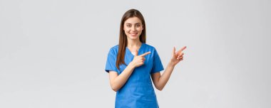 Sağlık çalışanları, virüsü, sigortayı ve ilaç konseptini engelleyin. Mavi önlüklü, gülümseyen hemşire ya da kadın doktor, parmaklarını aşağıya uzattı, Coronavirus haberleri hakkında bilgi verdi, bilgi verdi.