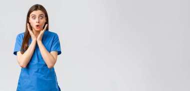 Sağlık çalışanları, virüsü, sigortayı ve ilaç konseptini engelleyin. Şaşırmış hemşire ya da kadın doktor mavi önlüklü, soluk soluğa endişeli görünüyor, yeni Cauvid-19 hastasının hastalandığını duyuyor, kameraya bakıyor