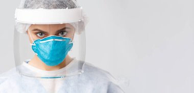Covid-19, virüsü önleme, sağlık çalışanları ve karantina konsepti. Kişisel koruyucu kostüm, solunum cihazı ve yüz kalkanı takmış ciddi, kararlı bir doktor ya da hemşireye yakın çekim.