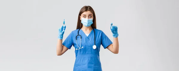 Covid-19, het voorkomen van virus, gezondheid, gezondheidswerkers en quarantaine concept. Opgewonden vrouwelijke verpleegkundige in blauwe scrubs, arts in kliniek met spuit en ampul met coronavirusvaccin — Stockfoto