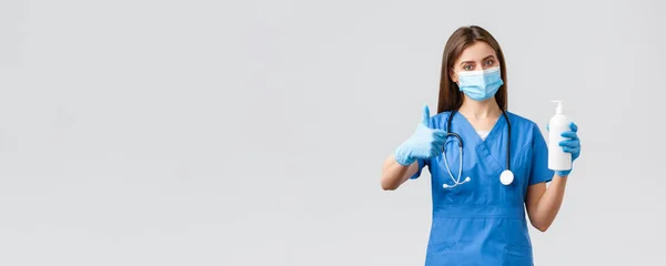 Covid-19, prévention du virus, de la santé, des travailleurs de la santé et concept de quarantaine. Médecine confiante, infirmière en blouse bleue avec masque médical et conseils à l'aide d'un désinfectant pour les mains, approbation du pouce — Photo