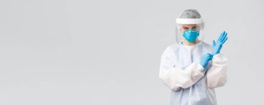 Covid-19, virüsün önlenmesi, sağlık, sağlık çalışanları ve karantina konsepti. Kişisel koruma ekipmanları içinde ciddi bir kadın doktor PPE, kalkan, yüz maskesi takıp hasta odasına giriyor.