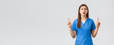 Sağlık çalışanları, virüsü, sigortayı ve ilaç konseptini engelleyin. Hayal kırıklığına uğramış ve kızgın kadın hemşire, mavi önlüklü doktor, pankarttan şikayet ediyor, parmaklarını havaya kaldırıyor, surat asıyor.