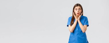 Sağlık çalışanları, virüsü, sigortayı ve ilaç konseptini engelleyin. Şaşırmış hemşire ya da kadın doktor mavi önlüklü, soluk soluğa endişeli görünüyor, yeni Cauvid-19 hastasının hastalandığını duyuyor, kameraya bakıyor