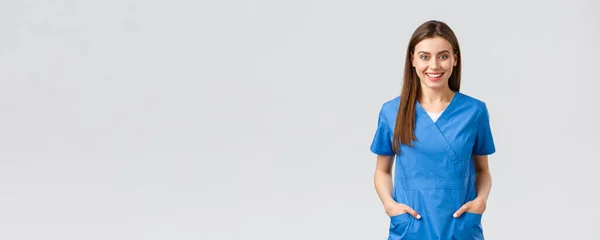 Медицинские работники, предотвратить вирус, страхование и медицина концепции. Веселый улыбающийся красивый доктор, медсестра в синем халате, интерн в больнице, позитивный, стоя на сером фоне — стоковое фото