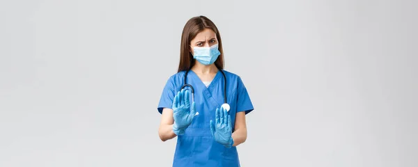 Covid-19, het voorkomen van virus, gezondheid, gezondheidszorg werknemers concept. Nee, bedankt. Ontevreden en terughoudend vrouwelijke verpleegkundige of arts in medisch masker en scrubs, stop, afwijzing of weigering teken — Stockfoto