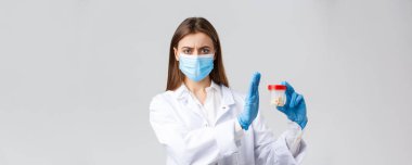 Covid-19, virüsü önleme, sağlık çalışanları ve karantina konsepti. Tıbbi maske takan endişeli ve hoşnutsuz doktor, eldivenler, reddedilmiş, onaylanmamış ilaç kullanımı, kötü haplar.